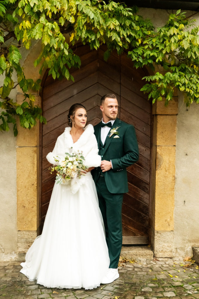 couple de mariés en robe longue blanche et costume vert foncé